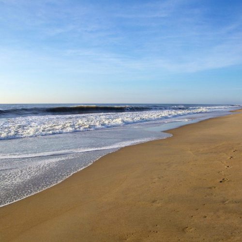 Footprints on sandy beach with the tide coming in
